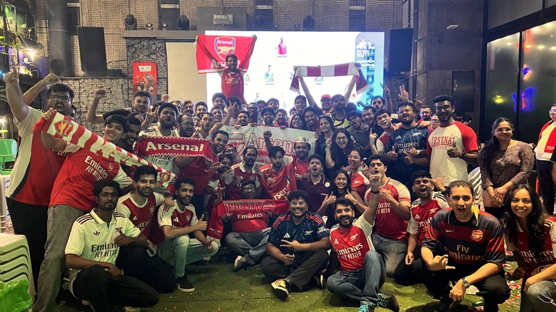 Arsenal Pune SC members packed together in kits and scarves at a Pune screening