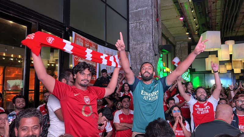 Two Gooners holding a scarf aloft at a Pune screening